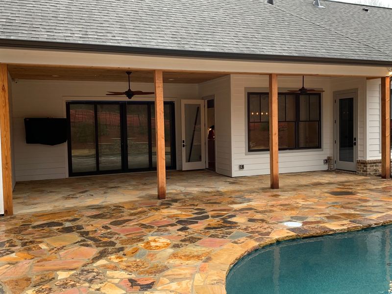Covered outdoor living with stone patio and pool